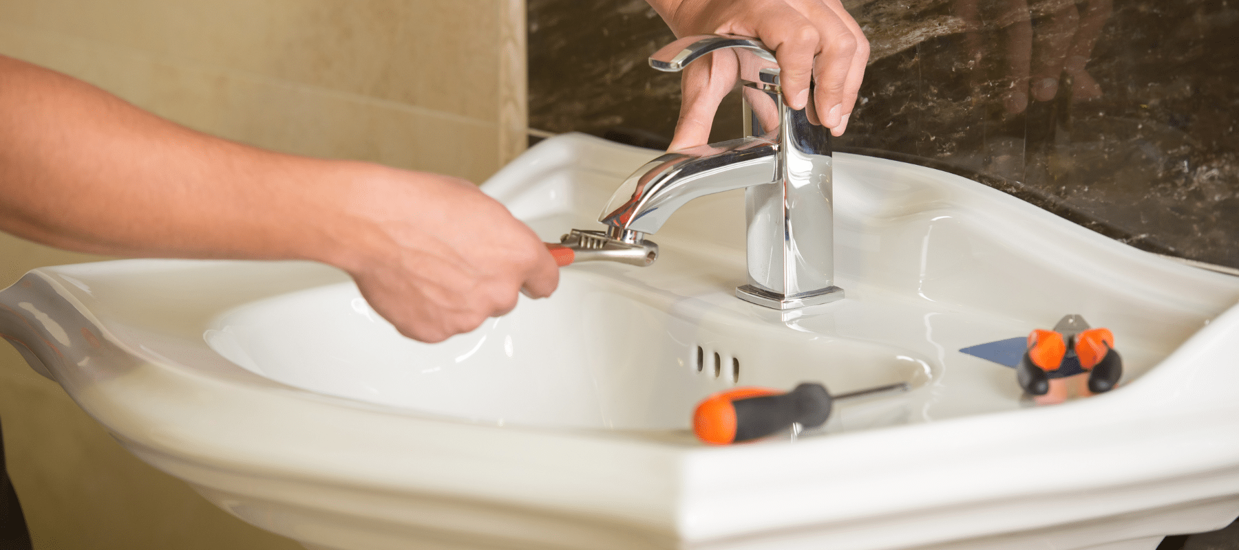 Plumber tightening a faucet in a white ceramic sink