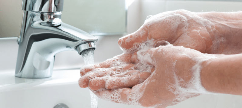 closeup of someone washing their hands with soap and water